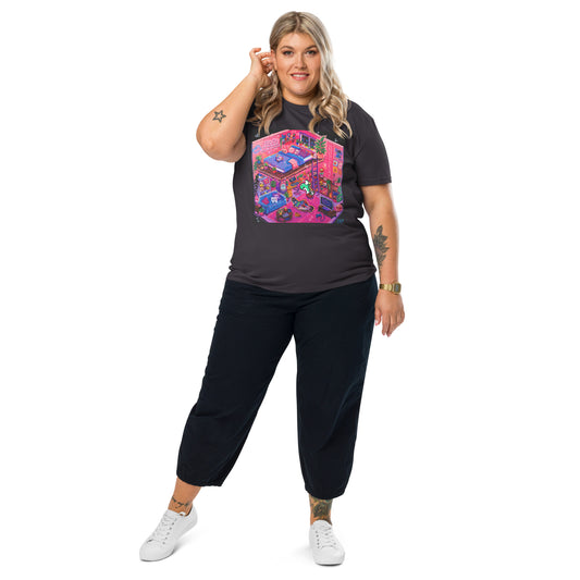 Colorful graphic T-shirt featuring the "Inside the Candy Decay Studio" artwork, showing a cozy pink loft bedroom and creative studio filled with plants, pigeons, retro gaming details, and playful pop surreal elements in vibrant neon colors.