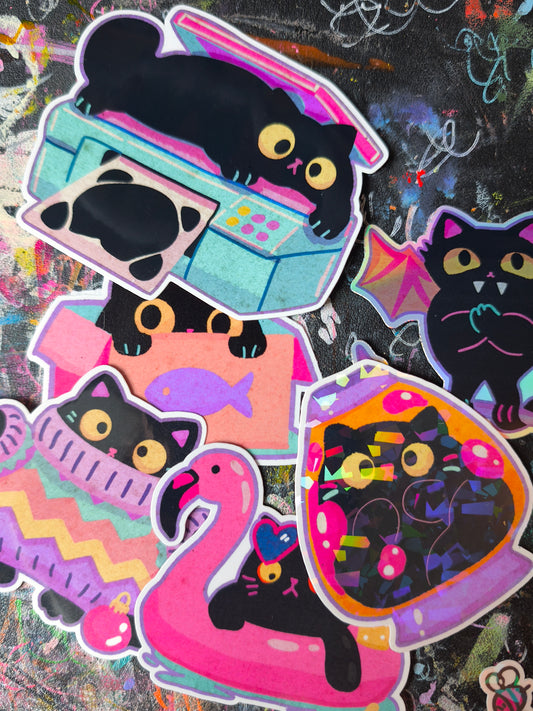 Close-up of all six black cat sticker designs with scanner, box, sweater, flamingo float, vampire and lava lamp