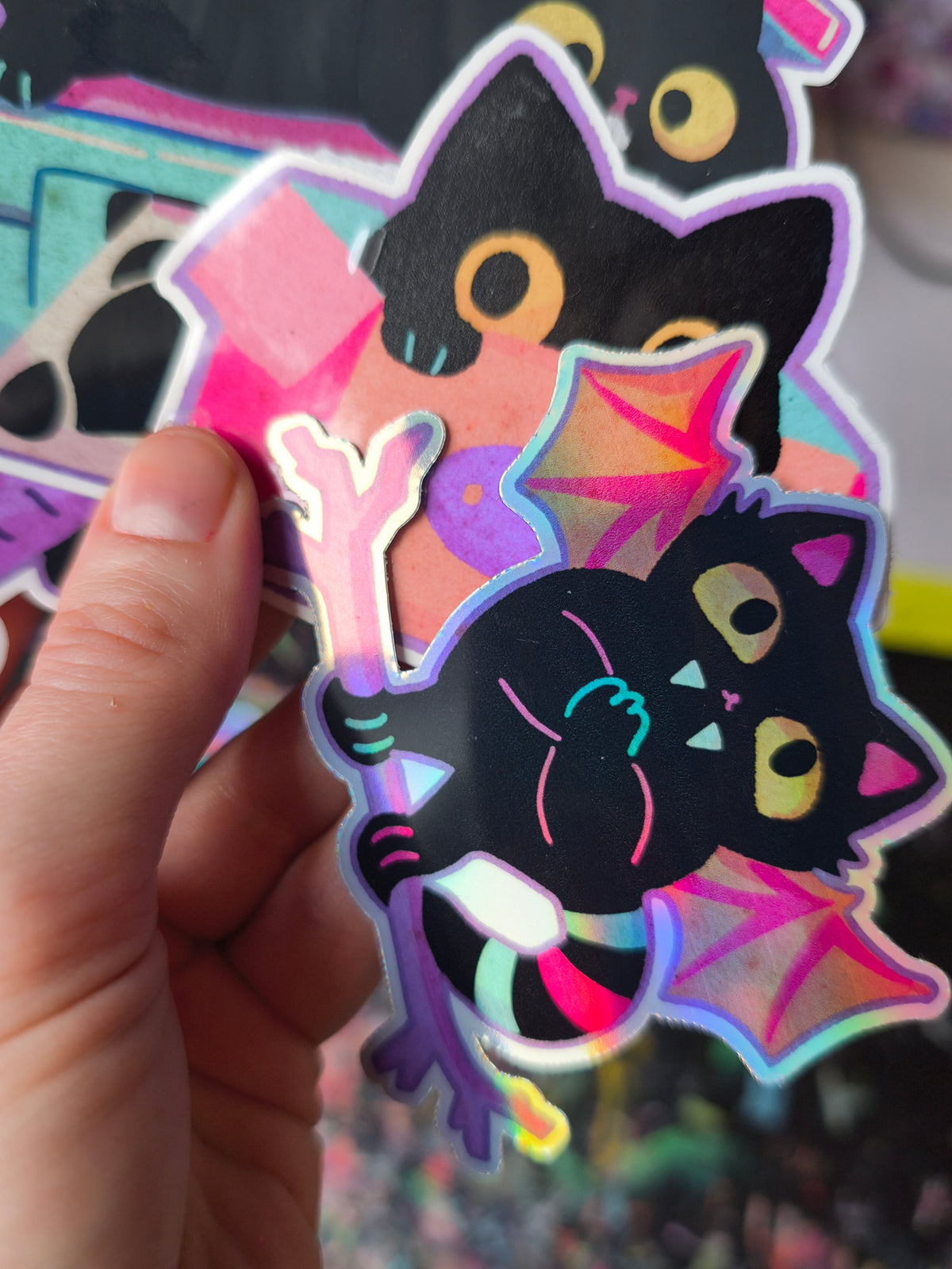 Close-up of black cats in a pink box and hanging upside down with vampire wings