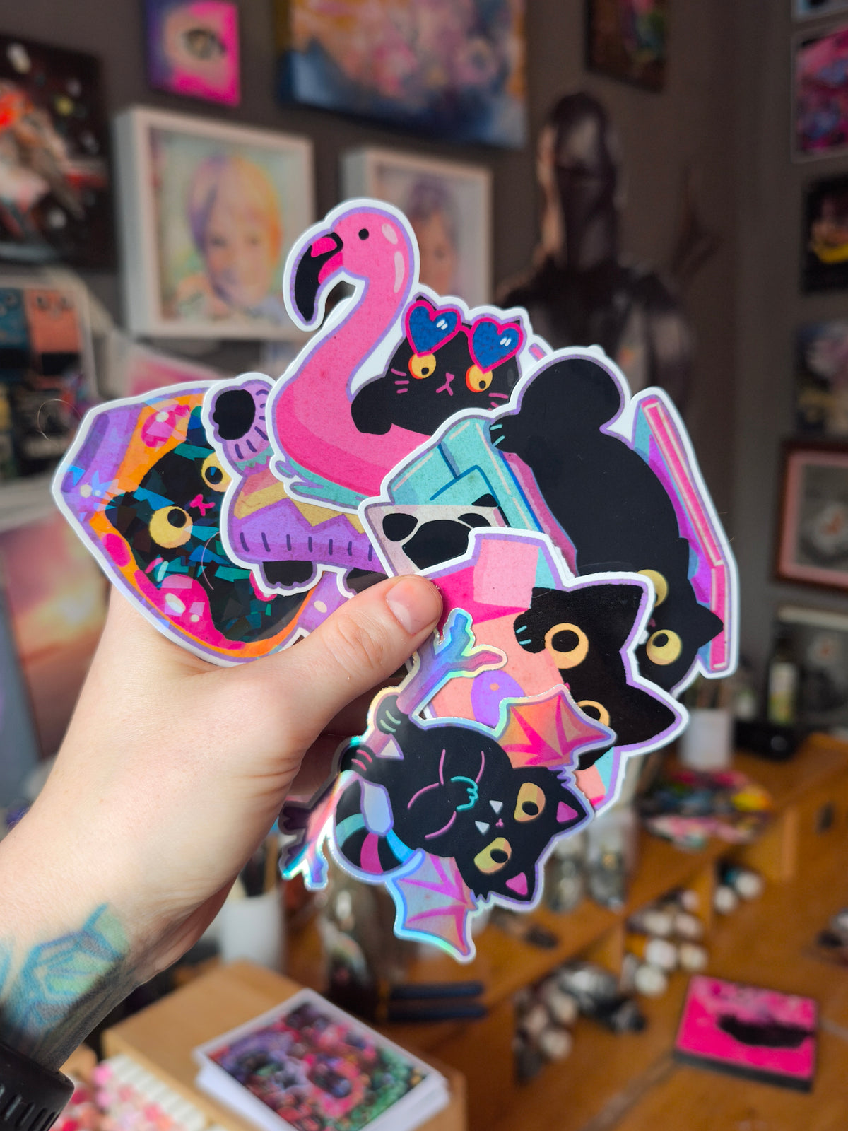The six black cat stickers held together in the artist's hand