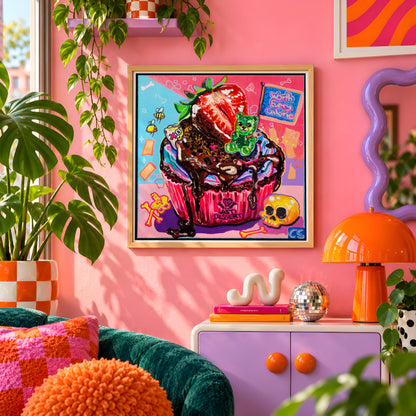 The Last Dessert wall art print framed on a pink wall, featuring a skull-topped cupcake with a gummy bear and a strawberry, Candy Decay style by Paintranger