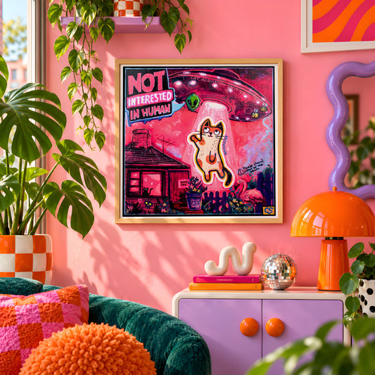 Cat Acquisition Unit 78 wall art print framed on a pink wall, featuring a cat being beamed up by a UFO labeled Not Interested in Human, Candy Decay style by Paintranger